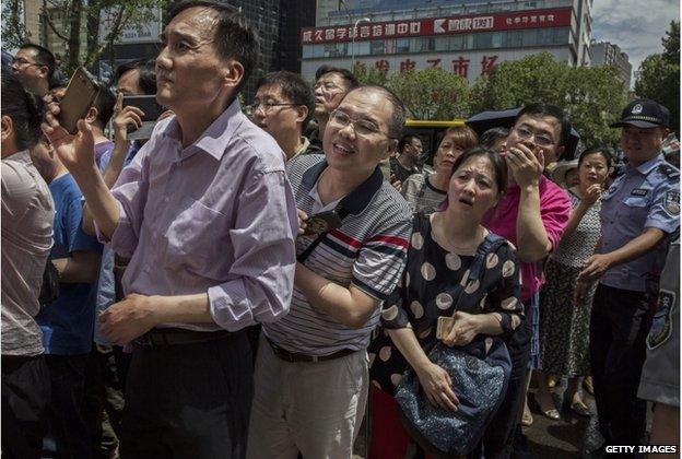 Parents of Chinese students wait and take pictures outside of the Beijing Renmin University Affiliated High School, one of the most prestigious in the country, as they wait for their children to finish writing the Gaokao on 7 June 2015 in Beijing, China