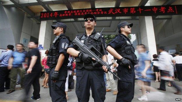 Armed policemen stand on patrol at the gate of a high school as students sit the 2014 college entrance exam of China, or the 'gaokao', in Wuhan, central China's Hubei province on 7 June 2014