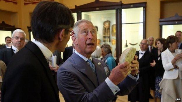 The Prince of Wales holds a marble head during a visit to Eton College near Windsor