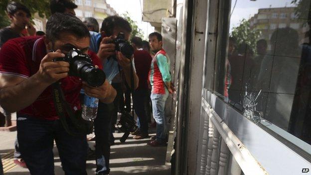 Journalists photograph bullet holes in a shop in Diyarbakir. 9 June 2015