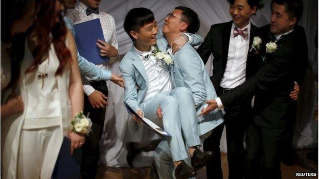 Duan Rongfeng (center R) lifts his new husband Li Tao in West Hollywood, LA (9 June 2015)