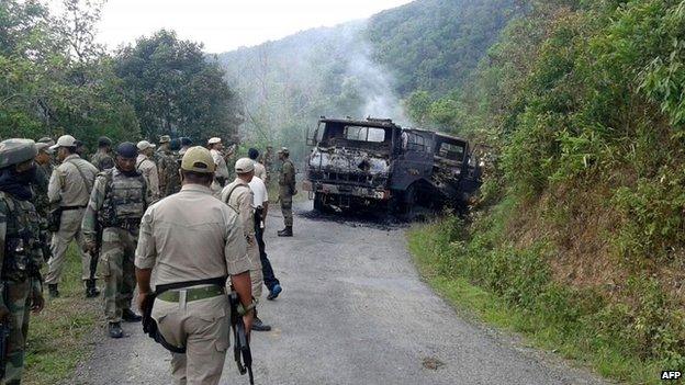 In this photograph taken on June 4, 2015, Indian security personnel stand alongside the smouldering vehicle wreckage at the scene of an attack on a military convoy in a remote area of Chandel district, about 120 kilometres (75 miles) southwest of northeastern Manipur"s state capital Imphal.