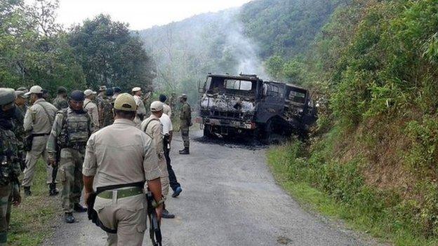 In this photograph taken on June 4, 2015, Indian security personnel stand alongside the smouldering vehicle wreckage at the scene of an attack on a military convoy in a remote area of Chandel district, about 120 kilometres (75 miles) southwest of northeastern Manipur"s state capital Imphal.