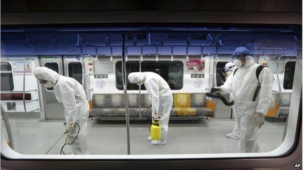 Workers wearing protective clothing spray an antiseptic solution throughout a subway car amid rising public concerns over the spread of MERS, Middle East Respiratory Syndrome, virus, at the subway car depot in Goyang, South Korea, Tuesday, 9 June 2015.