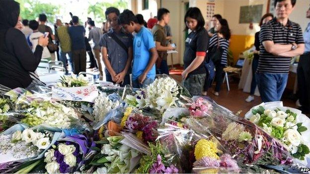 People look at bouquets of flowers in memory of the victims from an earthquake on Malaysia"s Mount Kinabalu, placed on a table at the Tanjong Katong Primary School in Singapore on 7 June 2015