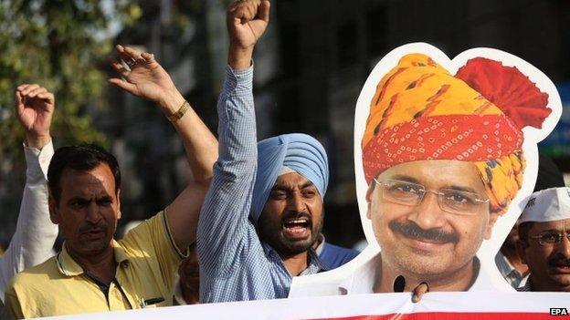 Activists of Aam Aadmi Party (AAP) shout slogans holding a cutout poster of Arvind Kejriwal