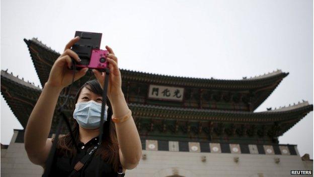 Chinese tourist wearing a mask to prevent contracting Middle East Respiratory Syndrome (MERS) takes a selfie in front of the main entrance of the Gyeongbok Palace in central Seoul, South Korea, 4 June 2015.