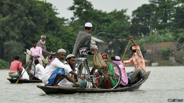 Indian villagers use a boat to travel through floodwater in Pokoriya village in Assam