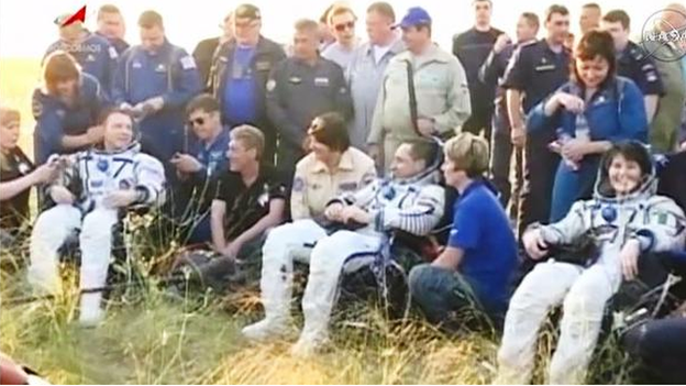 Astronauts Terry Virts, Anton Shkaplerov and Samantha Cristoforetti rest outside after landing