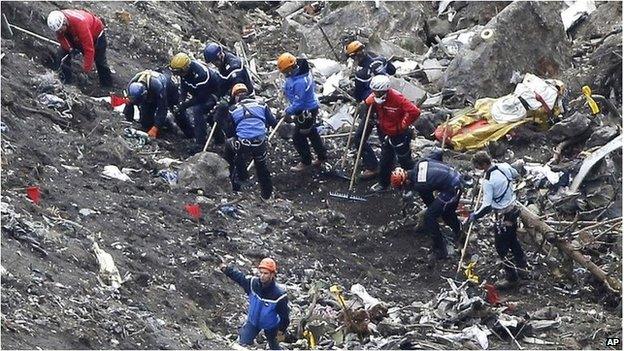 Rescue workers work on debris of the Germanwings jet at the crash site