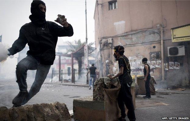 A Bahraini protester prepares to throw back a tear gas canister during clashes with police following a demonstration on February 13, 2015