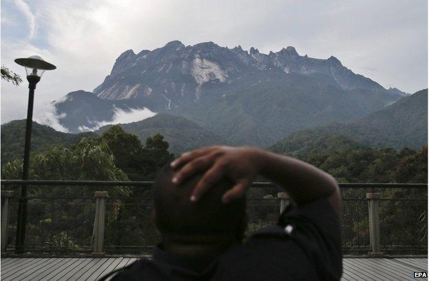 A policeman reacts as he sits facing the Kinabalu Mountain as a rescue mission continues for more than 130 climbers stranded on one of Southeast Asia's highest mountains after an earthquake, Sabah, in Kundasang, Malaysia, 6 June 2015.