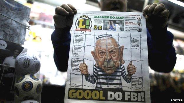 A man shows a Brazilian newspaper front page with a caricature of former President of the Brazilian Football Confederation (CBF), Jose Maria Marin, with a headline reading 'Goal of the FBI', in Sao Paulo (28 May 2015)