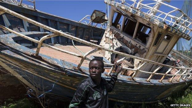 Eric Joseph, 27, a migrant from Nigeria stands in a "boat graveyard" by the port on April 22, 2015 in Lampedusa, Italy