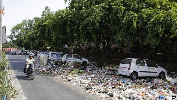 A otorist rides past a garbage strewn road in Delhi