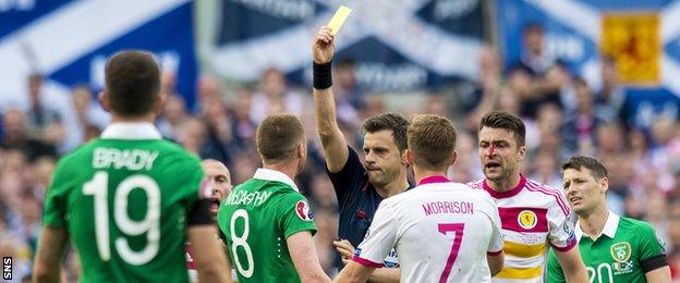 Republic of Ireland's James McCarthy is shown a yellow card by referee Nicola Rizzoli for an elbow into Russell Martin's face