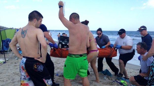 Emergency responders assist a teenage girl at the scene of a shark attack in Oak Island on June 14, 2015