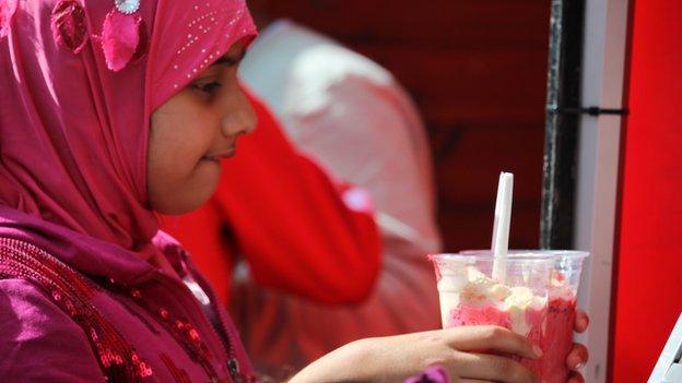 A young girl in pink gets some dessert