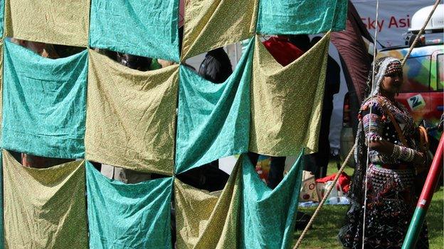 A woman stands by pieces of cloth sewn together