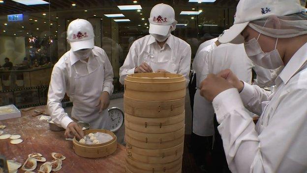 Workers in open kitchen preparing dumplings