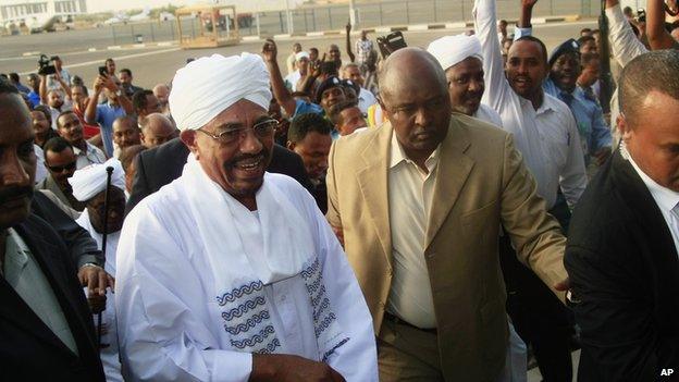 Hundreds of supporters welcome Sudanese President Omar al-Bashir, centre left, on his arrival from South Africa as he walks through the crowd at the airport in Khartoum