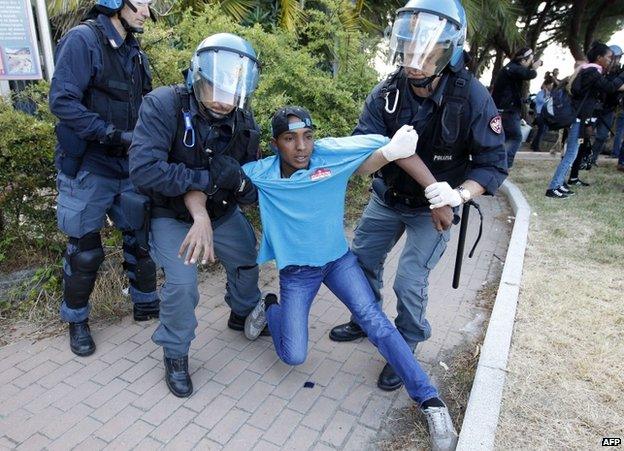 Italian police restrain a migrant on the border with France at Ventimiglia