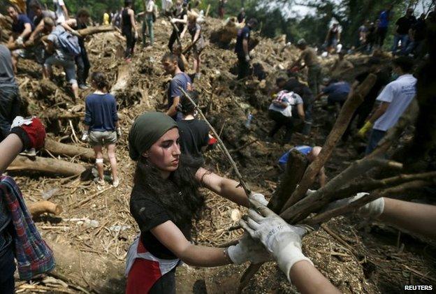 Volunteers clean debris around a buried emergency car in Tbilisi, Georgia, 16 June 2015