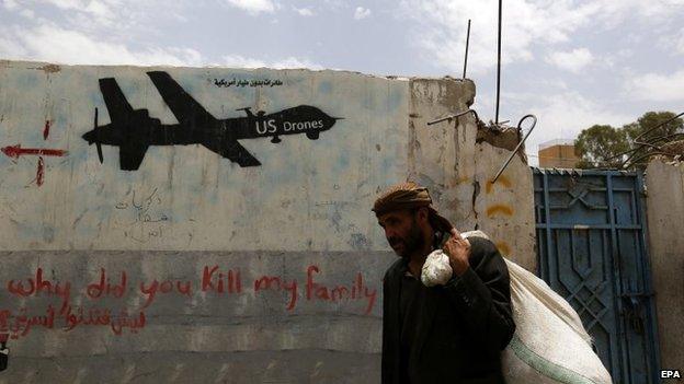 A man walks past graffiti condemning the US drone campaign in Yemen (16 June 2015)