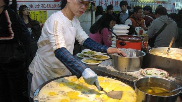 Stall owner cooking oyster omelette at a night market in Taiwan