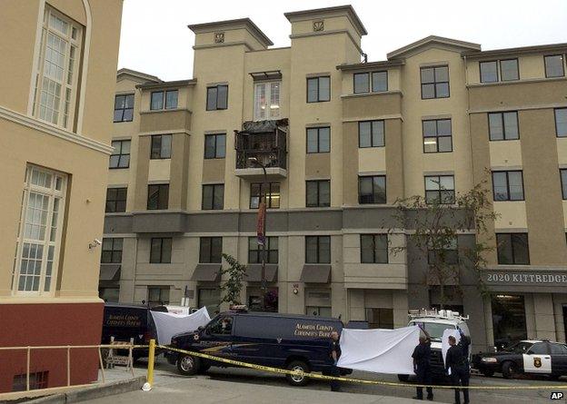 The apartment building with a car that says "Alameda County Coroner's Bureau" parked in the front