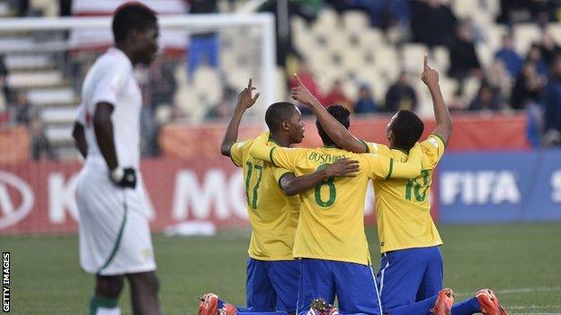 A Senegal player stands dejected as Brazil's players celebrate