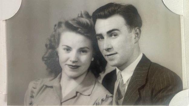 A black and white photo of Betty on the left with wavy hair, red lipstick and a blouse. Her fiancé Maurice wears a tie and a pinstripe suit. They are in their twenties.