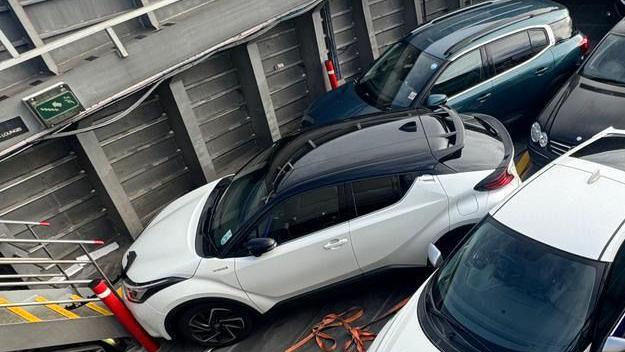 A view from above of a number of vehicles, one white car had crashed into the stair case.