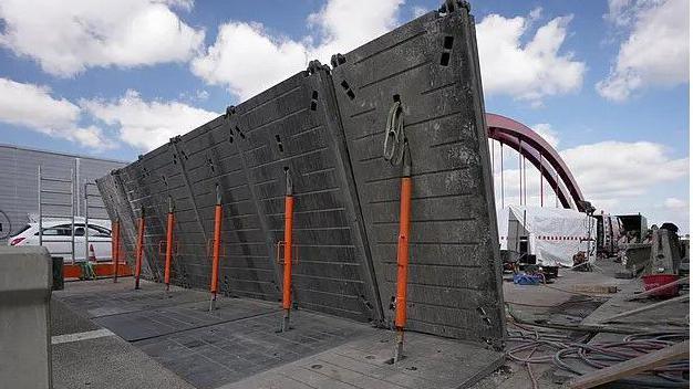 Temporary bridging plates are being held up by rods. They are in the middle of a road which is undergoing maintenance.
