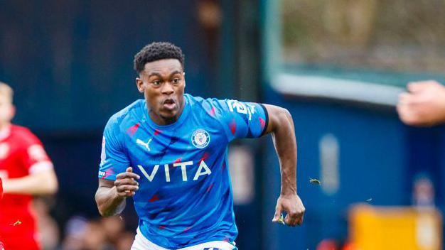 Isaac Olaofe, wearing number 25 for Stockport County, is in possession of the ball during the Sky Bet League 2 match between Stockport County and Swindon Town at Edgeley Park Stadium in Stockport, England, on February 24, 2024.