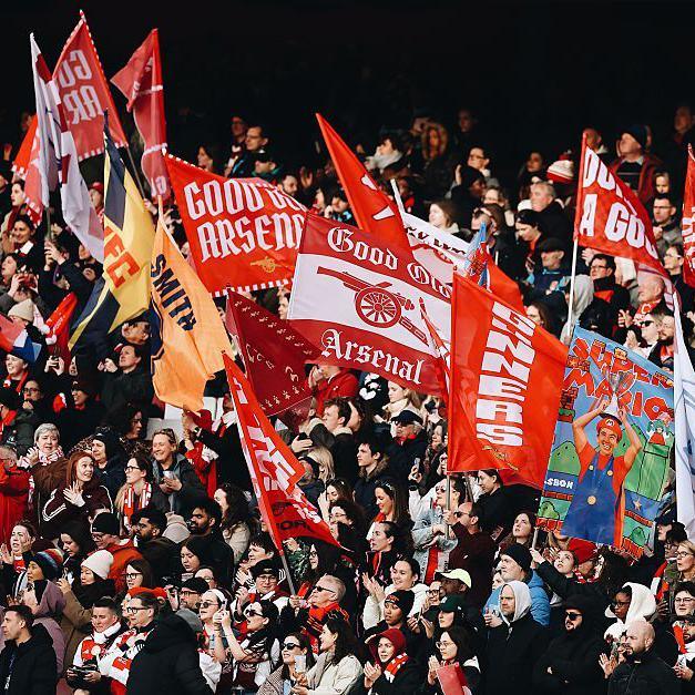 Arsenal fans wave flags in the stand before a WSL north London derby v rivals Spurs at the Emirates