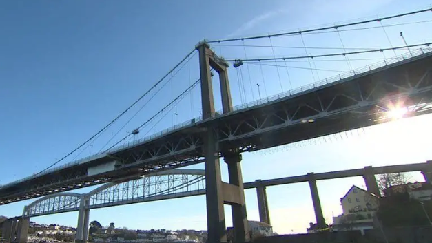 A suspension bridge and another bridge behind it with sun shining on the right.