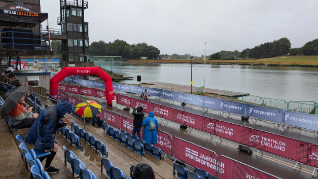 A seating area, a finish line and some lanes in the foreground, with a lake at the rear 