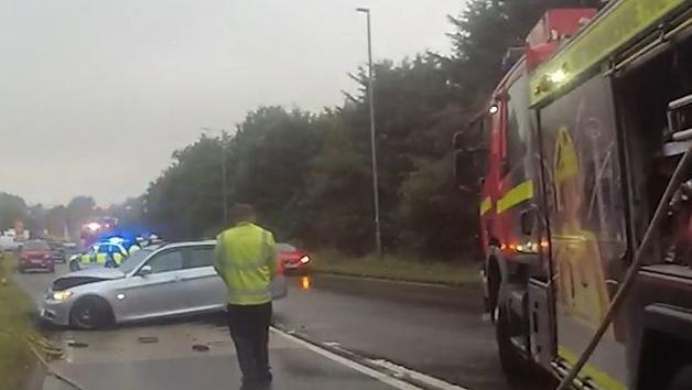 Emergency services on a road after a crash, with a silver vehicle