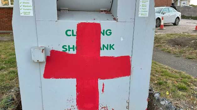 A red cross painted onto a clothing and shoe bank.