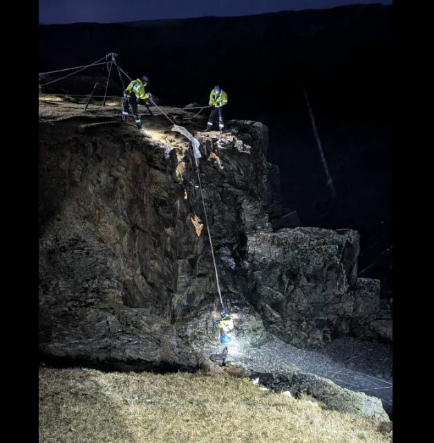 Maoir-chladaich a' cleachdadh ròpannan airson cu a tha glacte aig bonn creige a thoirt a-nìos 