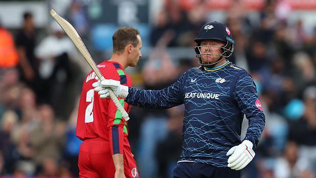 Jonny Bairstow raises his bat after a blistering half-century against Lancashire