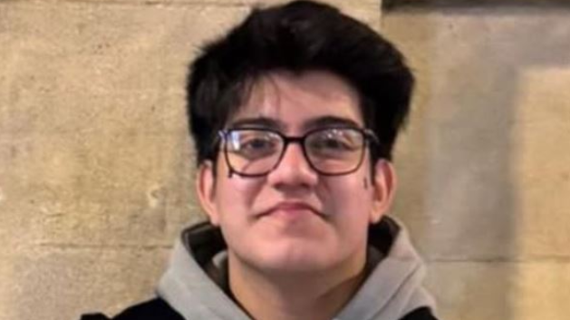 Taha Ali Soomro - the teenager has black hair and black rimmed glasses and wears a grey hoodie and a black gilet.