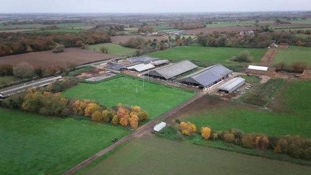 Aerial picture of three milking barns in the countryside surrounded by fields 