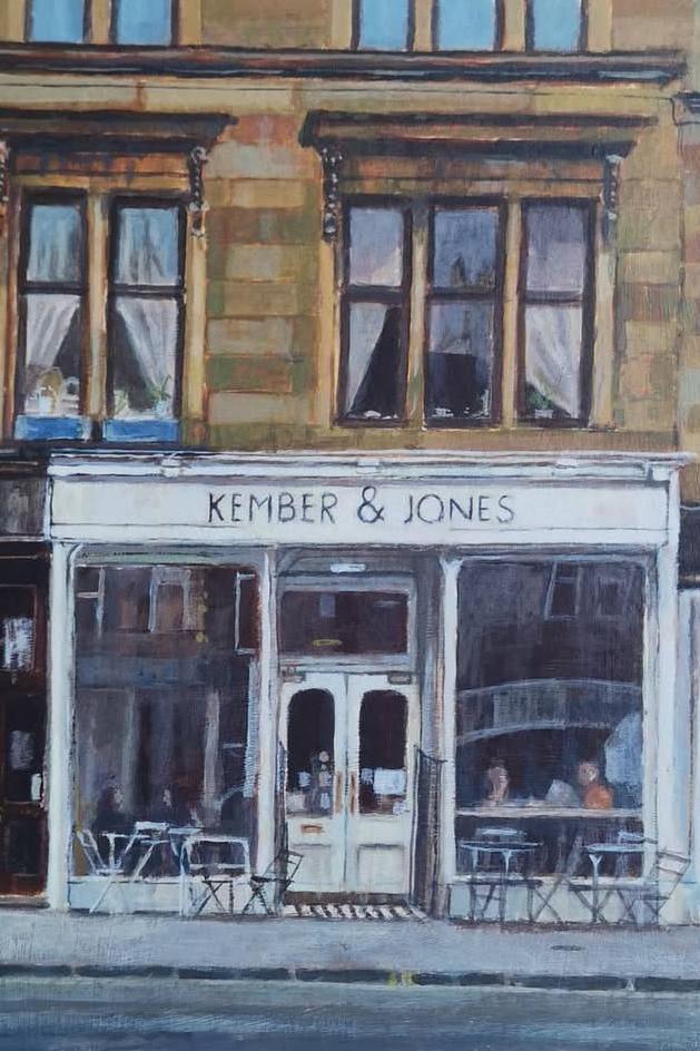 An acrylic painting of Kember & Jones on Glasgow's Byres Road. The café is painted white with two large windows and a door in the centre. Tables and chairs are set out on the pavement, while people sit in the windows.