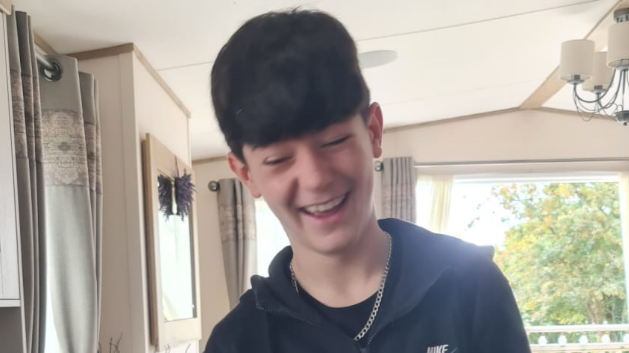 Osian, wearing a blue top and a silver necklace, smiling