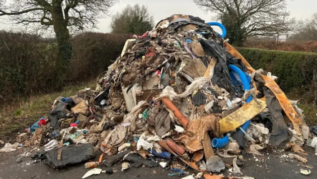 A pile of fly-tipped rubbish which is difficult to tell what it is, including materials, plastics and general rubbish. 