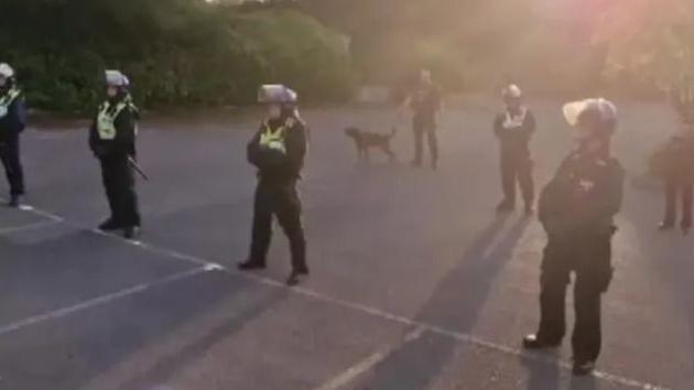 Police in riot gear standing in a row in a car park