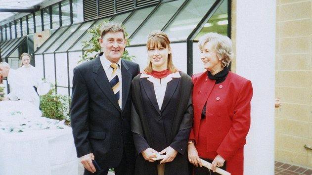 Bryson and Margaret Garlick pictured with their daughter Deborah on her graduation day in 1996. Deborah is in a gown, her mother is looking at her smiling. Her father is smiling into the camera.