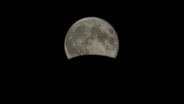 A large moon with a curved section cut out, against a black background